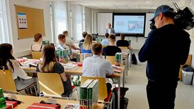 Schüler blicken im Unterrichtsraum auf ein digitales Whiteboard.